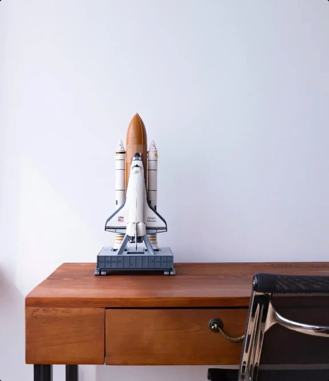 Tiny toy rocketship on brown desk.